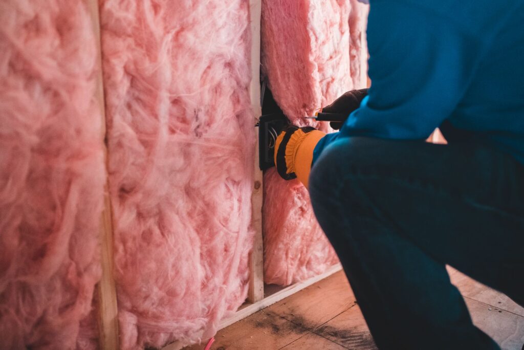 Ouvrier posant de la laine de verre pour isoler une maison, illustrant la rénovation énergétique DPE F ou G