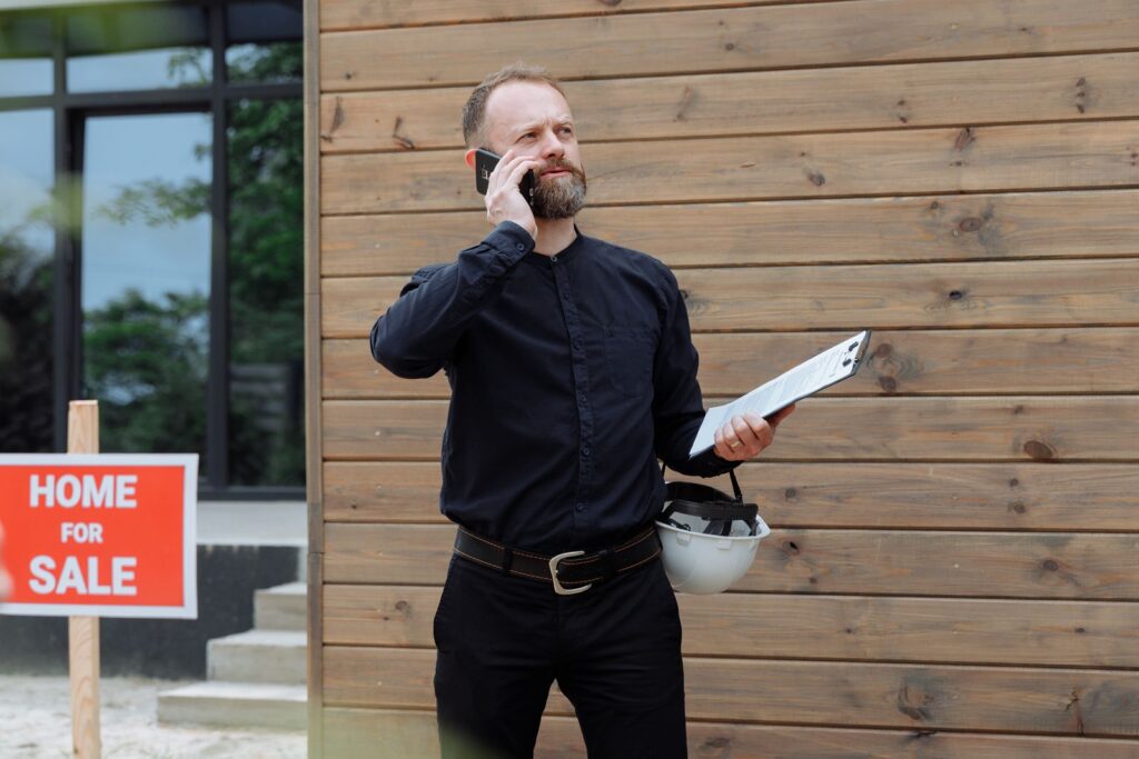 Agent immobilier en appel téléphonique devant une maison, illustrant les leads vendeurs dans les réseaux