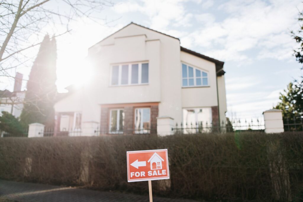 Panneau "à vendre" planté devant une maison, illustrant le délai de vente