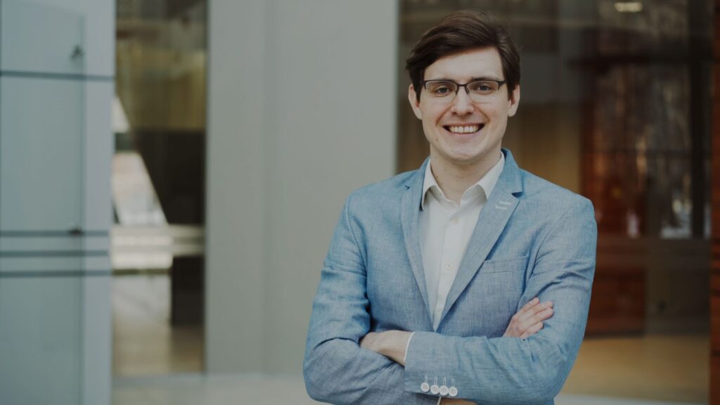 Professionnel souriant et confiant en costume, illustrant la reconversion en mandataire immobilier